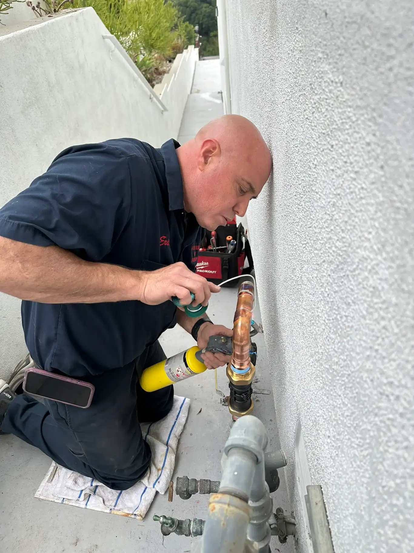 Professional plumber repairing outdoor piping system for home water line, demonstrating plumbing repair services for residential or commercial properties.