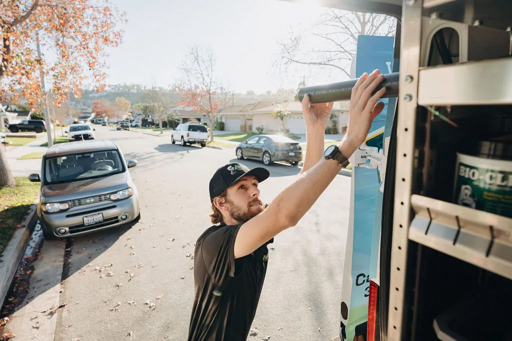 technician unloading pipes from service truck